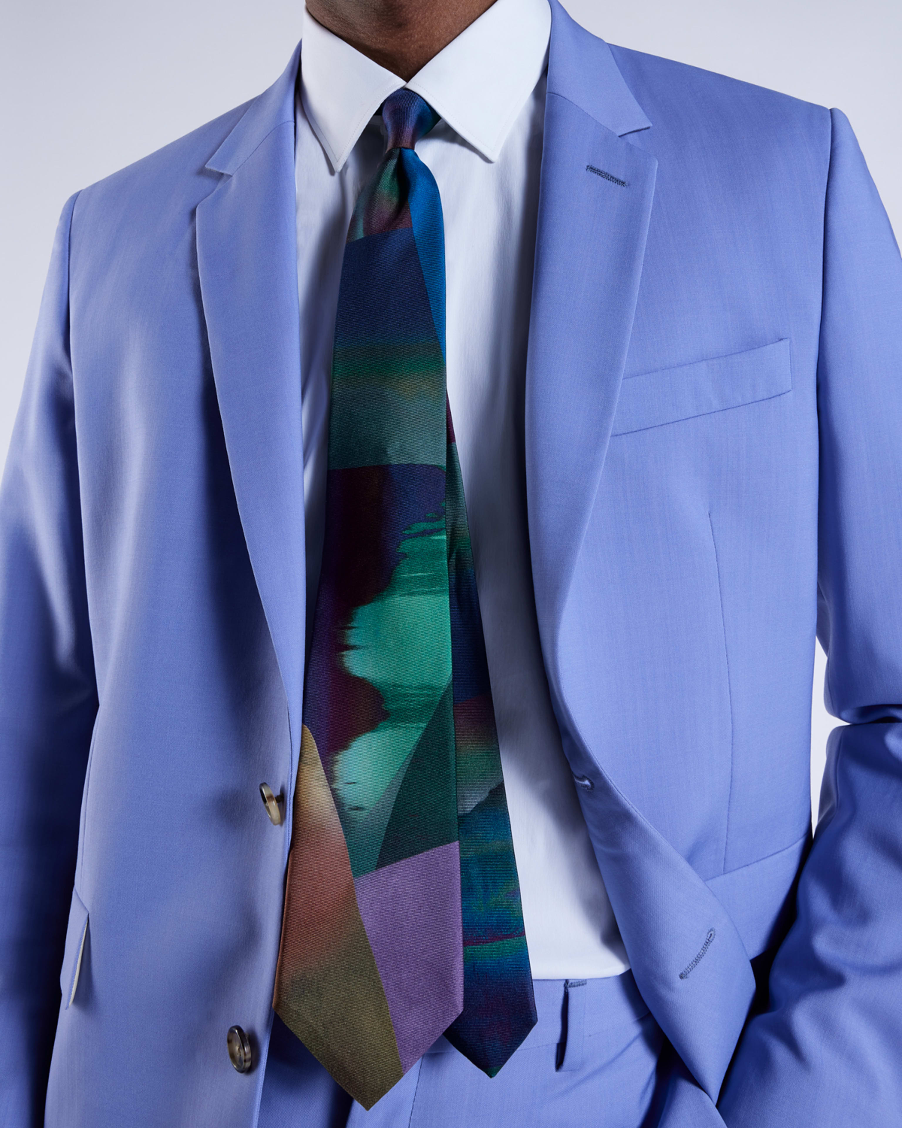 a male model wearing a light blue wedding suit jacket with a white shirt, paired with a colourful patterned statement tie