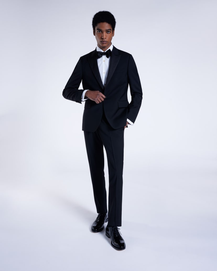 a male model wearing a full designer black tuxedo with white shirt and black bow tie